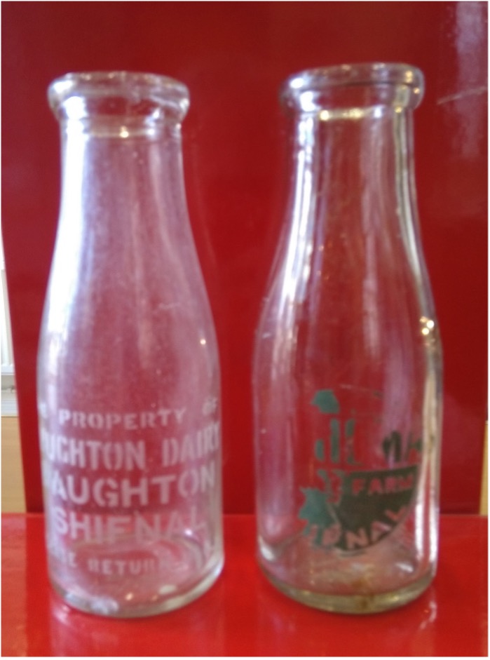Two Haughton Farm milk bottles on a red background