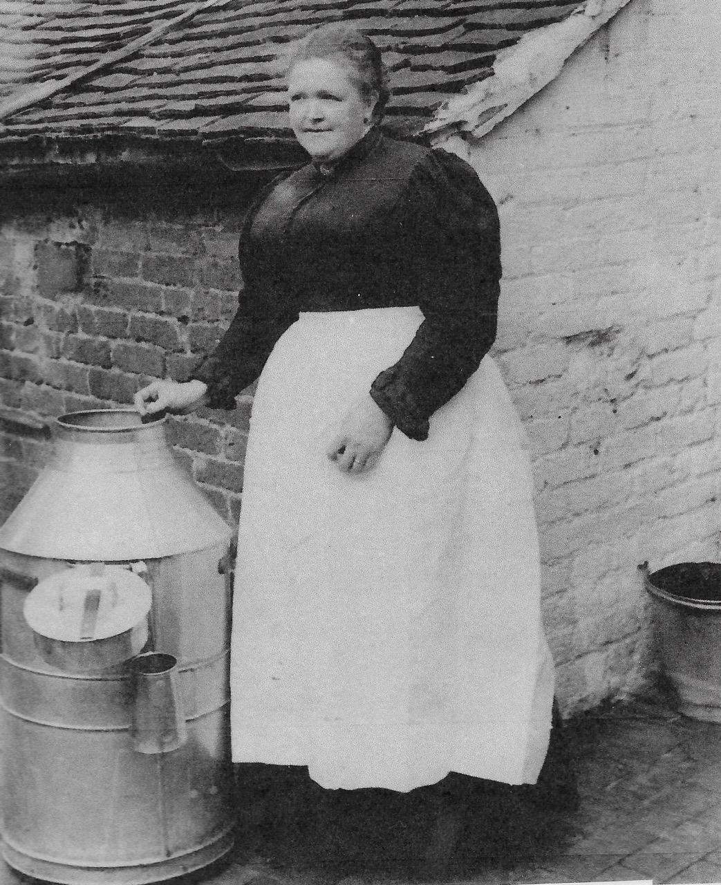 Black and white photograph, dating to the early 1920s, shows Mrs. Mary Lee with a milk urn.